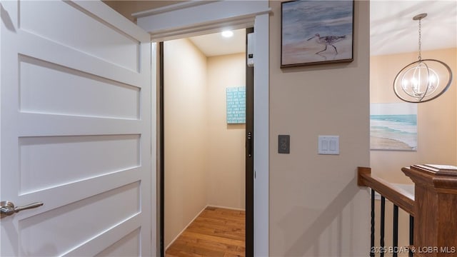 hall featuring light hardwood / wood-style floors and a notable chandelier