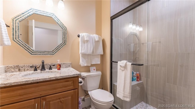 bathroom featuring toilet, vanity, and an enclosed shower