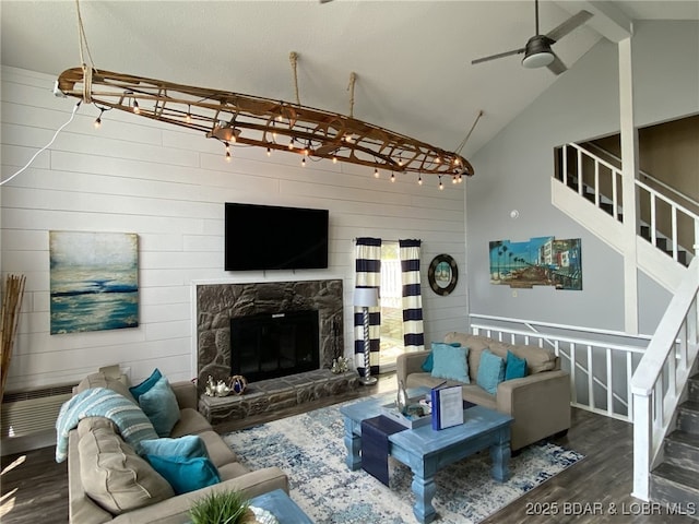 living room featuring dark wood-type flooring, beam ceiling, high vaulted ceiling, wooden walls, and a fireplace