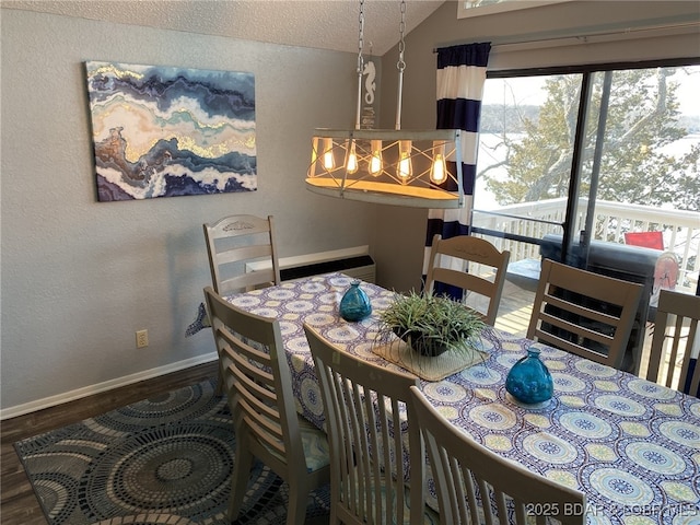 dining space featuring lofted ceiling, dark wood-type flooring, an inviting chandelier, and a textured ceiling