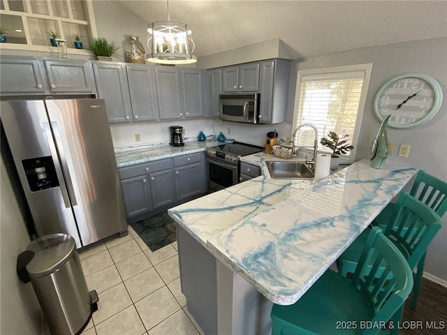 kitchen with gray cabinets, appliances with stainless steel finishes, decorative light fixtures, sink, and kitchen peninsula