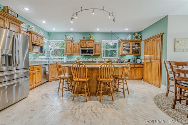 kitchen with stainless steel appliances, a wealth of natural light, a kitchen island, and a breakfast bar area