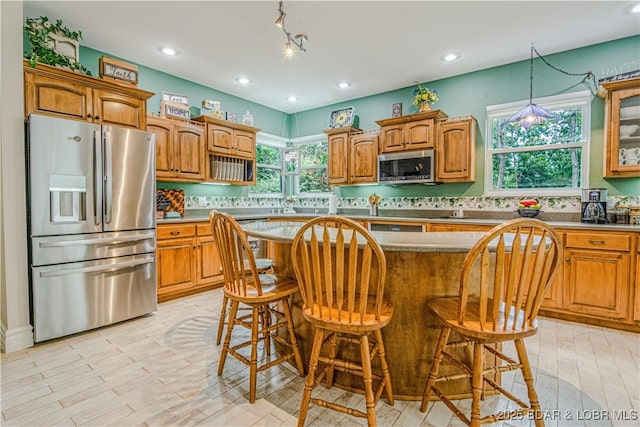 kitchen with plenty of natural light, a breakfast bar, a center island, and appliances with stainless steel finishes