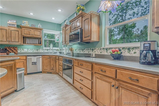 kitchen with appliances with stainless steel finishes, sink, and light wood-type flooring