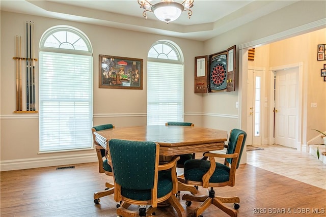 dining area with a tray ceiling and light wood-type flooring