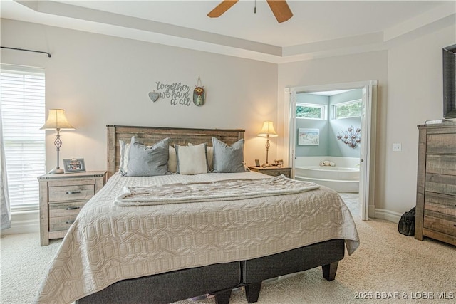 carpeted bedroom featuring ceiling fan, a tray ceiling, and multiple windows