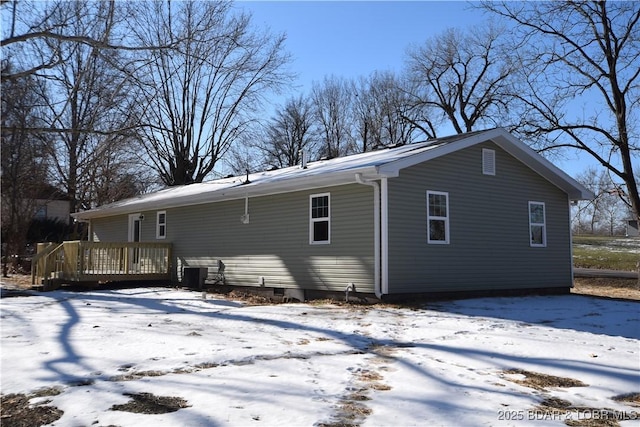 snow covered back of property featuring central air condition unit and a deck