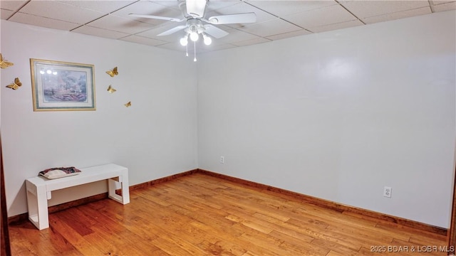 spare room with ceiling fan, baseboards, a paneled ceiling, and light wood-style floors