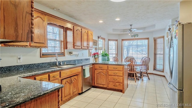 kitchen featuring sink, a textured ceiling, appliances with stainless steel finishes, kitchen peninsula, and dark stone counters