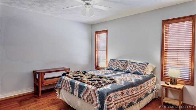 bedroom with a ceiling fan, baseboards, and wood finished floors