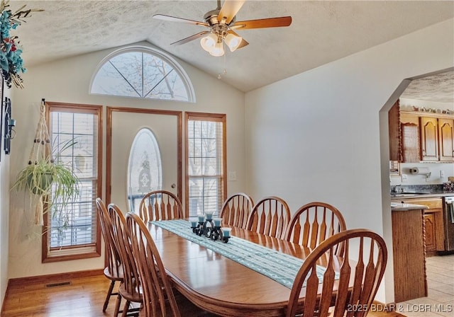 dining space featuring vaulted ceiling, a wealth of natural light, ceiling fan, and light wood-type flooring