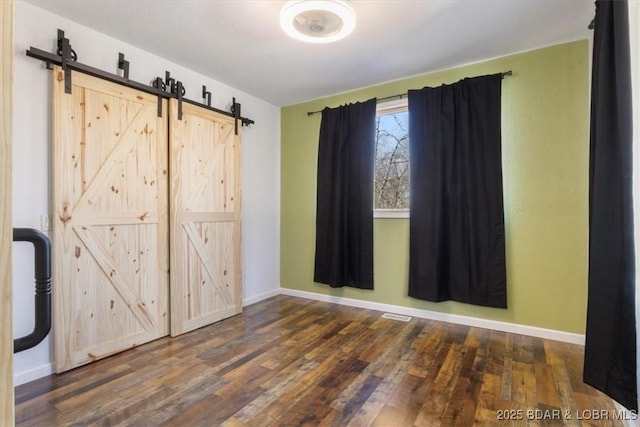 unfurnished room featuring a barn door and dark hardwood / wood-style floors