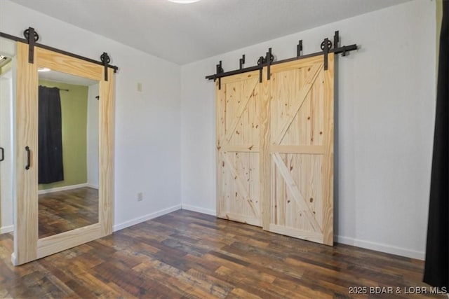 spare room featuring a barn door and dark hardwood / wood-style flooring