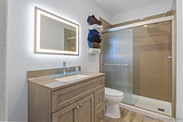 bathroom with vanity, hardwood / wood-style flooring, toilet, and walk in shower