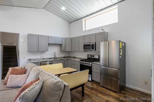 kitchen featuring appliances with stainless steel finishes, dark wood-type flooring, sink, and light stone counters