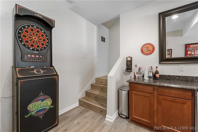 bar featuring dark stone countertops and light hardwood / wood-style floors