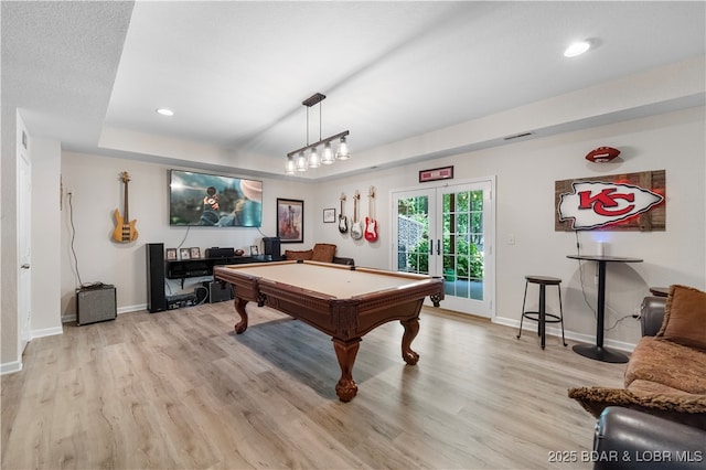 playroom featuring french doors, pool table, light wood-type flooring, and a tray ceiling