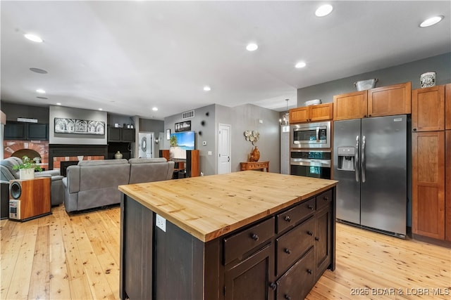 kitchen with a center island, appliances with stainless steel finishes, butcher block counters, and light wood-type flooring