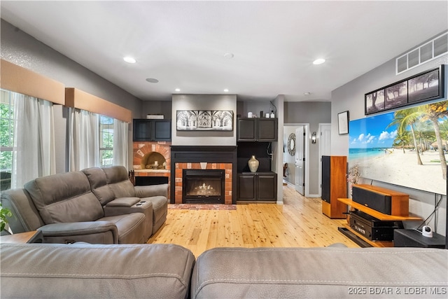 living room featuring a brick fireplace and light hardwood / wood-style floors