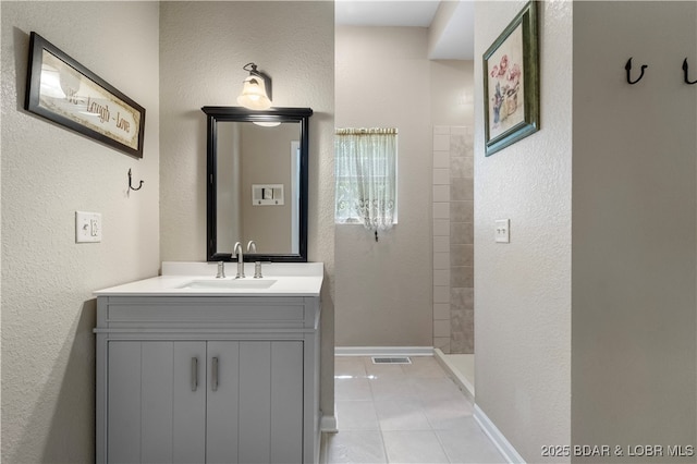 bathroom with tile patterned floors, vanity, and a tile shower