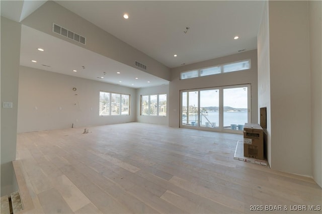 unfurnished living room featuring a water view and light hardwood / wood-style flooring