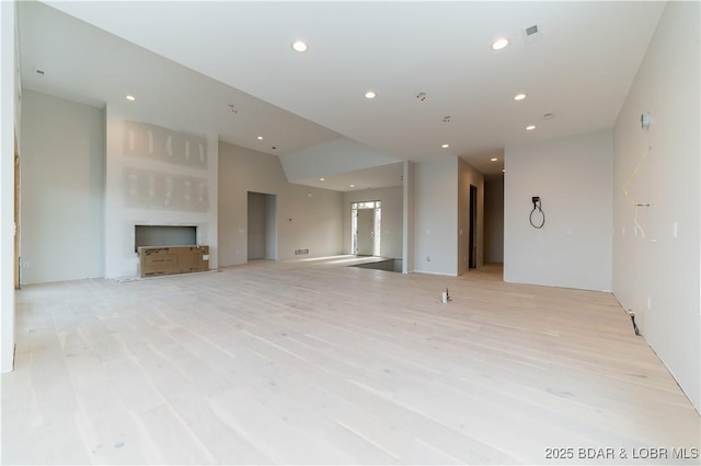 unfurnished living room featuring vaulted ceiling and light wood-type flooring