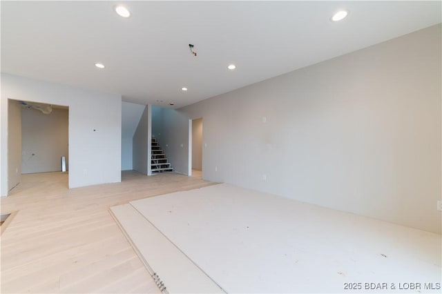 empty room with light wood-type flooring, stairs, and recessed lighting