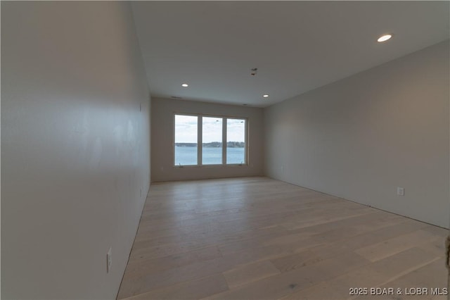 empty room featuring light wood-type flooring and a water view