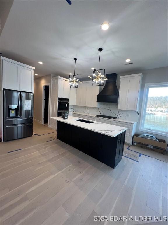 kitchen featuring light countertops, backsplash, white cabinets, custom exhaust hood, and black appliances
