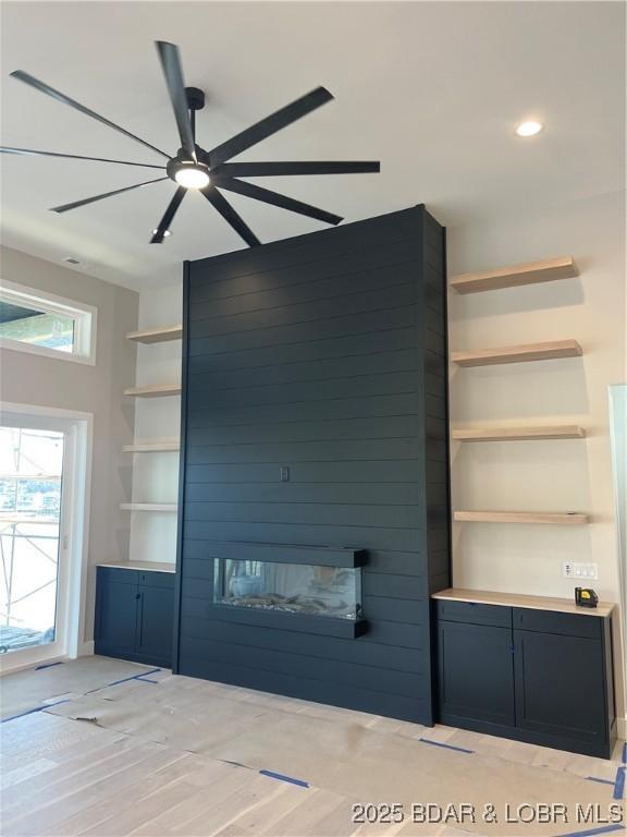 unfurnished living room with recessed lighting, light wood-type flooring, a ceiling fan, built in features, and a fireplace