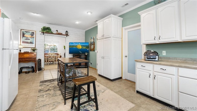 kitchen featuring white cabinetry, white fridge, light tile patterned floors, and crown molding