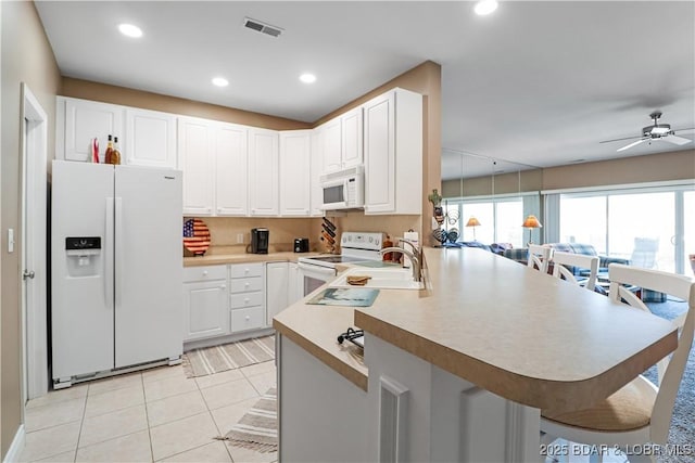 kitchen with white cabinetry, white appliances, kitchen peninsula, and light tile patterned floors