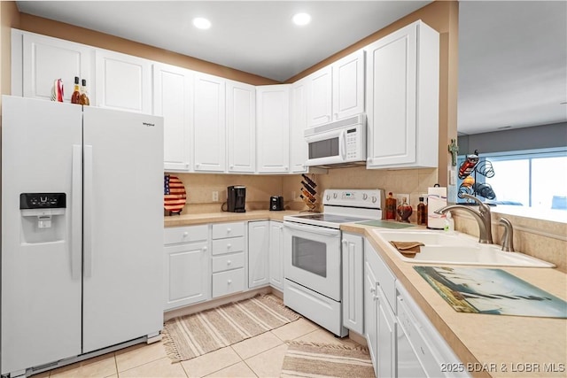 kitchen with sink, light tile patterned floors, white cabinets, and white appliances