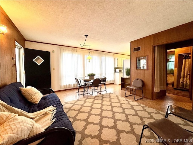 living room featuring crown molding, wooden walls, and a textured ceiling