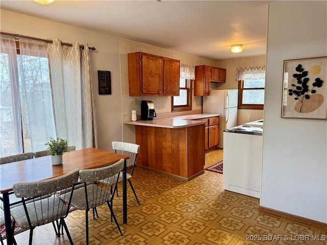 kitchen featuring white refrigerator, range, and kitchen peninsula