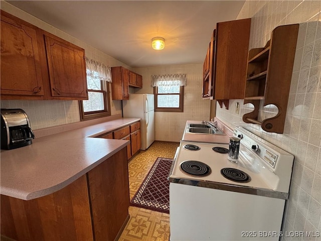 kitchen with sink, white appliances, and kitchen peninsula