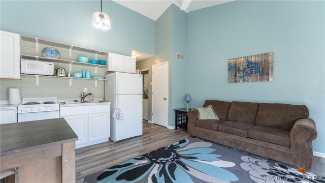 living room featuring sink, hardwood / wood-style flooring, and high vaulted ceiling