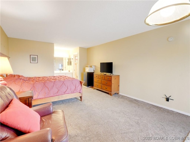 bedroom featuring baseboards, ensuite bathroom, and light colored carpet