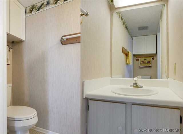 bathroom with vanity, toilet, and a textured ceiling