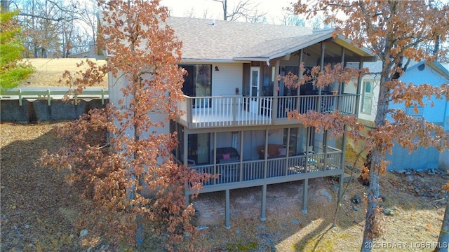 rear view of house featuring a balcony and roof with shingles