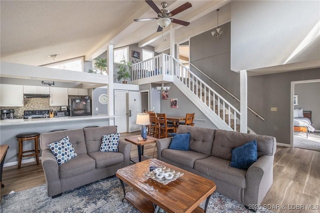 living room featuring beam ceiling, hardwood / wood-style flooring, ceiling fan with notable chandelier, and high vaulted ceiling