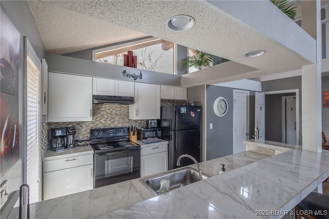 kitchen with sink, light stone counters, black appliances, white cabinets, and vaulted ceiling