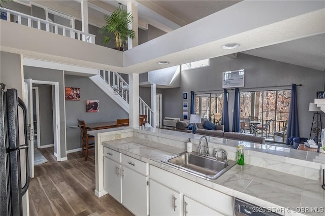 kitchen featuring high vaulted ceiling, sink, white cabinets, black fridge, and dark wood-type flooring