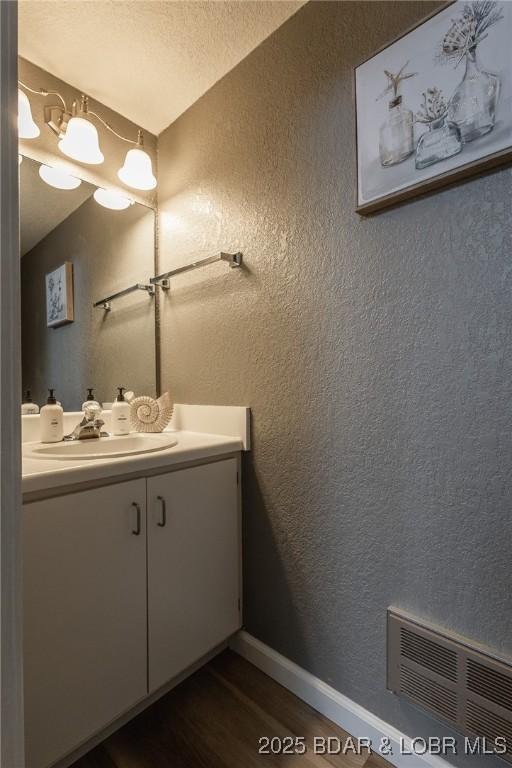 bathroom featuring hardwood / wood-style flooring, vanity, and a textured ceiling