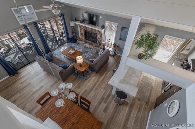 living room featuring hardwood / wood-style flooring, ceiling fan, lofted ceiling, and a fireplace