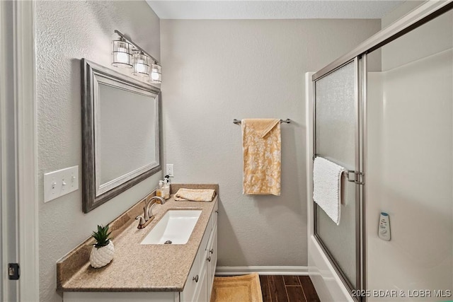 bathroom featuring enclosed tub / shower combo, wood-type flooring, and vanity