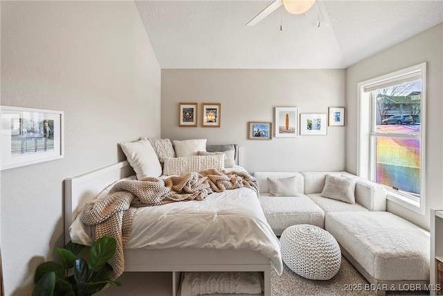 bedroom featuring ceiling fan, vaulted ceiling, and a textured ceiling