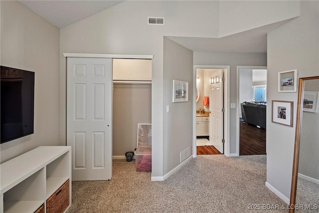 bedroom featuring lofted ceiling, carpet flooring, connected bathroom, and a closet