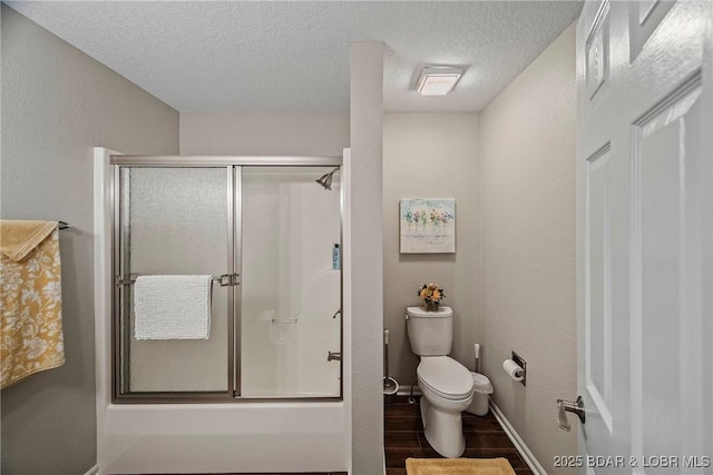 bathroom with an enclosed shower, hardwood / wood-style flooring, a textured ceiling, and toilet