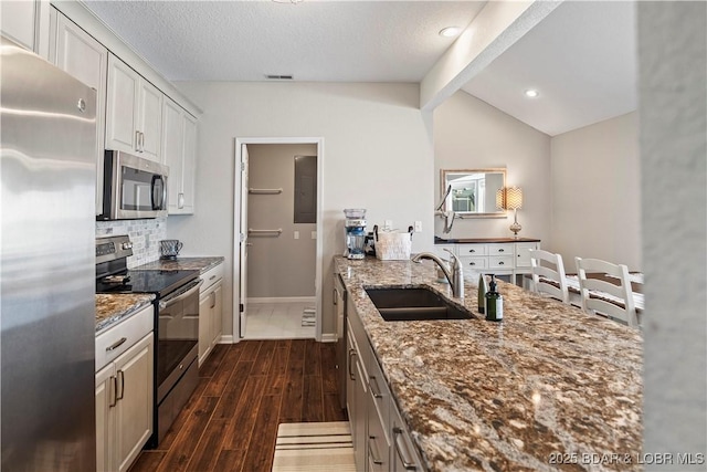 kitchen featuring stainless steel appliances, white cabinetry, sink, and light stone counters